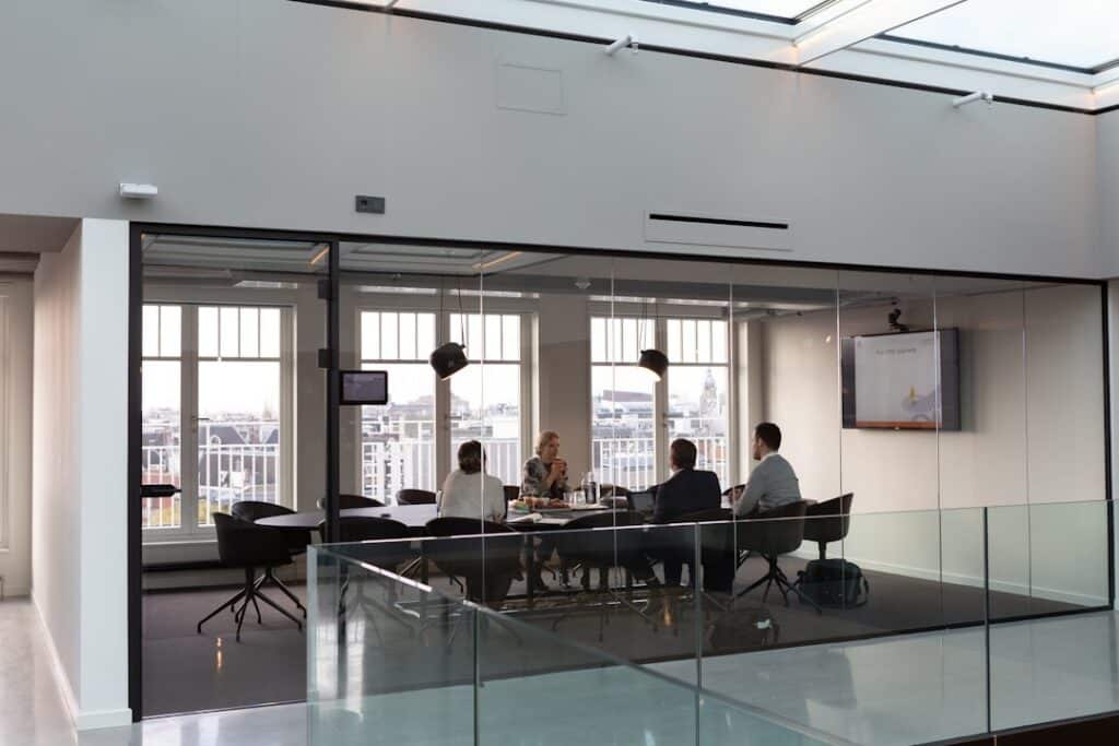 Four professionals collaborate around a conference table with monitors.
